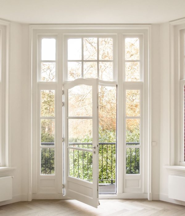 Access to a small balcony of a modern house with a view of the street, wooden windows and a door